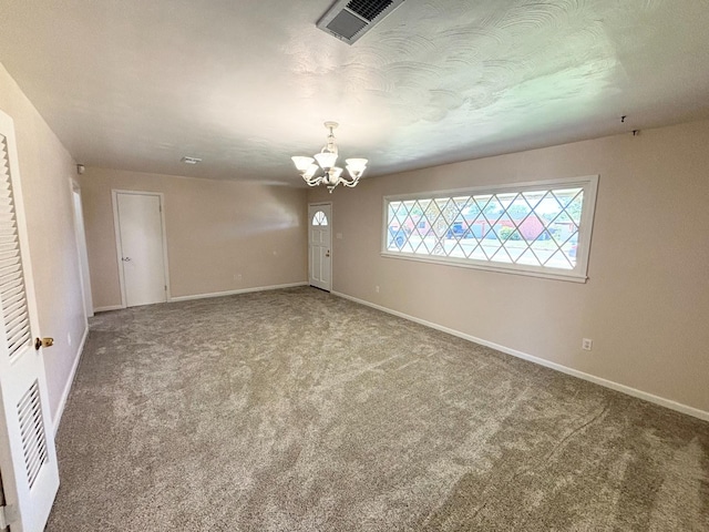 empty room featuring a textured ceiling, carpet, and a notable chandelier