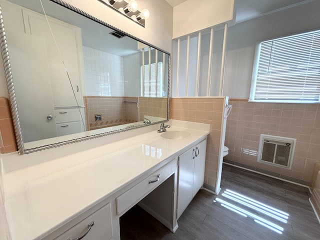 bathroom featuring hardwood / wood-style floors, heating unit, tile walls, vanity, and toilet