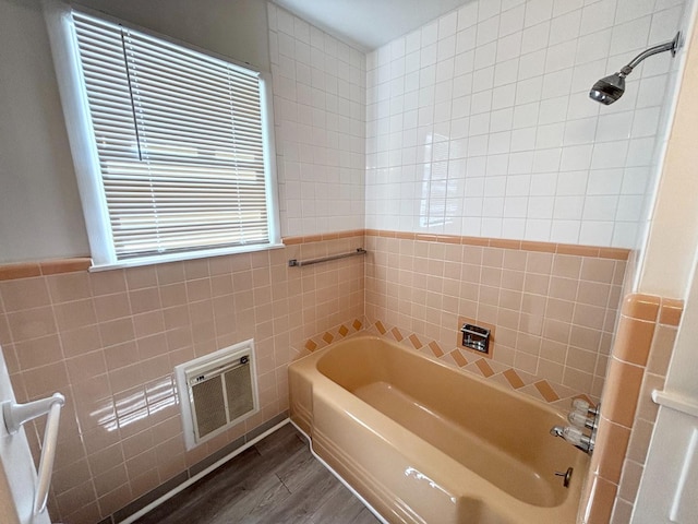 bathroom with tile walls, hardwood / wood-style flooring, and shower / bathing tub combination