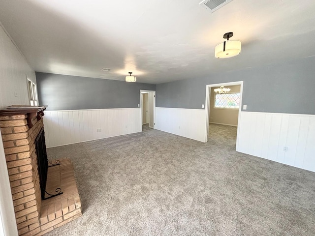 unfurnished living room featuring a fireplace, carpet floors, and a notable chandelier