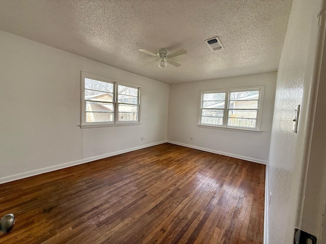 empty room featuring a healthy amount of sunlight, dark hardwood / wood-style floors, ceiling fan, and a textured ceiling