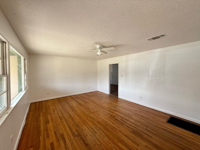 unfurnished room featuring dark wood-type flooring, ceiling fan, and a textured ceiling