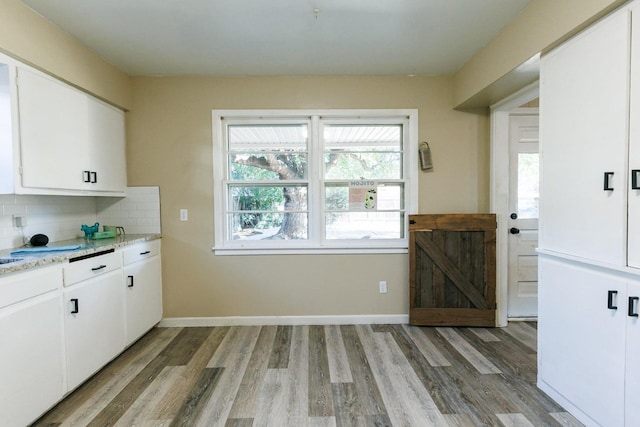 kitchen featuring white cabinetry, light stone counters, light hardwood / wood-style floors, and decorative backsplash