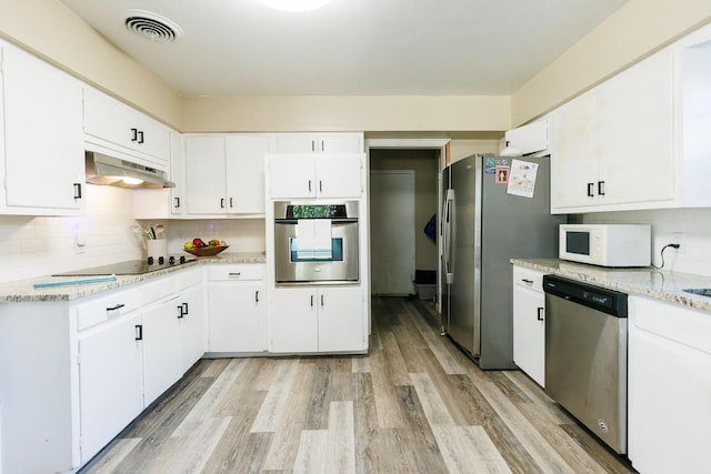 kitchen with appliances with stainless steel finishes, ventilation hood, backsplash, white cabinets, and light wood-type flooring