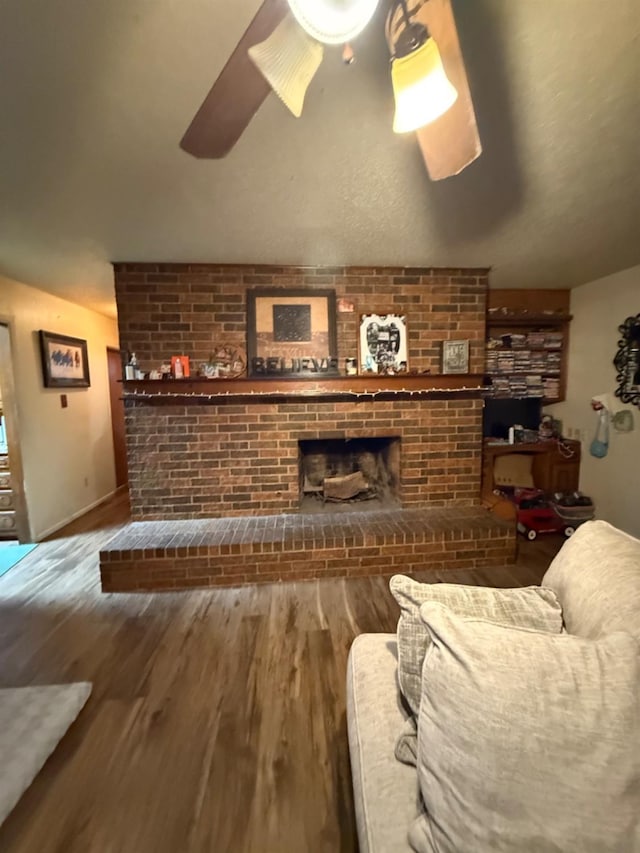 living room featuring ceiling fan, wood-type flooring, and a fireplace