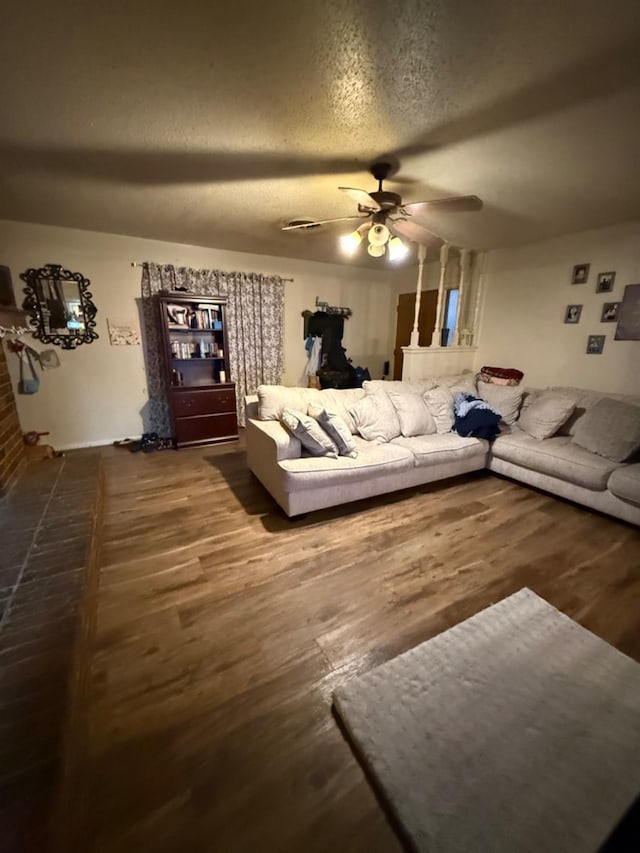 living room with ceiling fan, dark hardwood / wood-style floors, and a textured ceiling