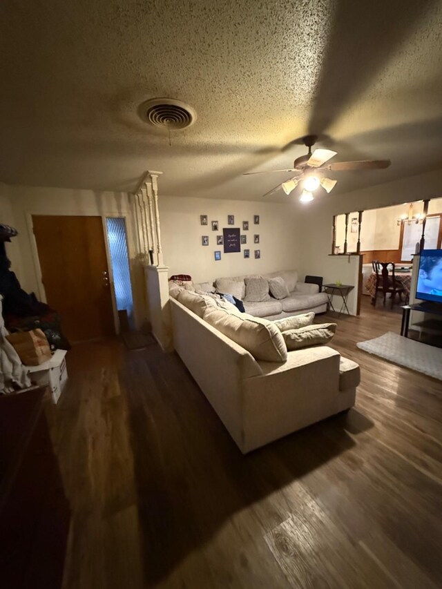 living room featuring ceiling fan, dark hardwood / wood-style floors, and a textured ceiling