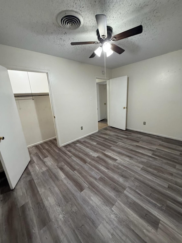 unfurnished bedroom featuring ceiling fan, a closet, dark hardwood / wood-style floors, and a textured ceiling