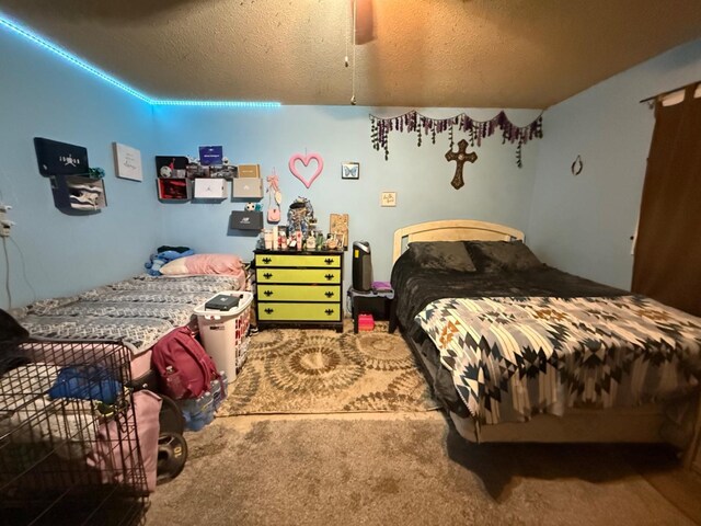 bedroom featuring ceiling fan, carpet floors, and a textured ceiling