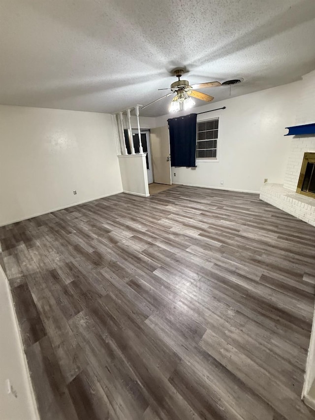 unfurnished living room featuring wood-type flooring, a textured ceiling, ceiling fan, and a fireplace