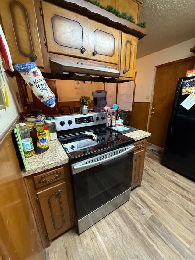 kitchen featuring electric stove, black refrigerator, a textured ceiling, and light wood-type flooring