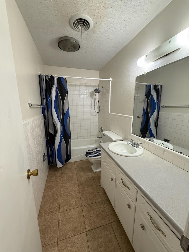 full bathroom featuring tile patterned floors, toilet, a textured ceiling, tile walls, and vanity