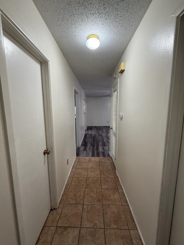 corridor with dark tile patterned flooring and a textured ceiling