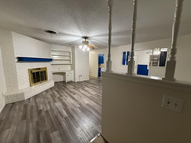 unfurnished living room featuring ceiling fan, a textured ceiling, a fireplace, and wood-type flooring