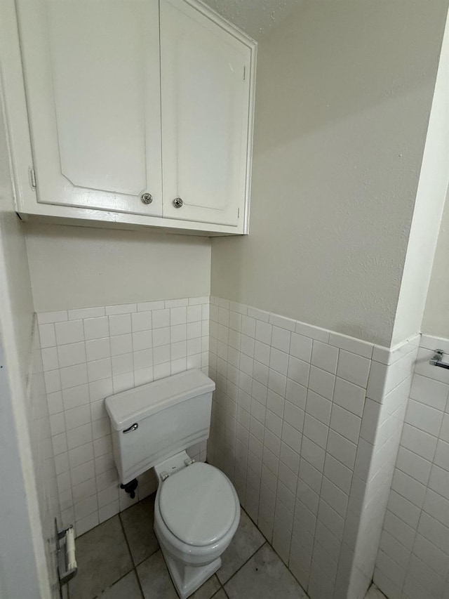 bathroom featuring tile patterned flooring, tile walls, and toilet