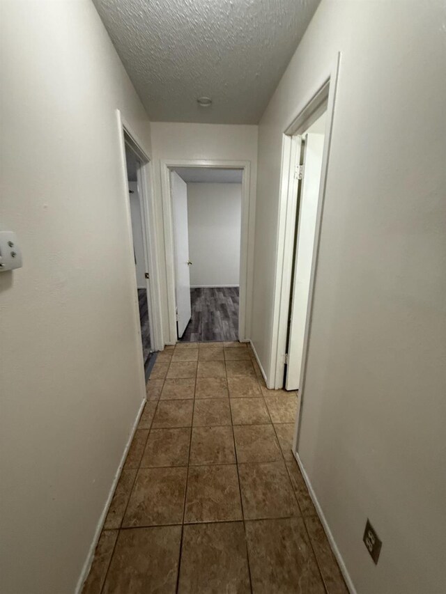 corridor with tile patterned floors and a textured ceiling