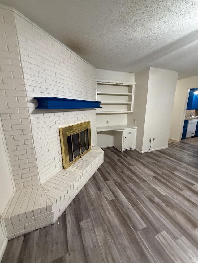 unfurnished living room with a brick fireplace, wood-type flooring, and a textured ceiling