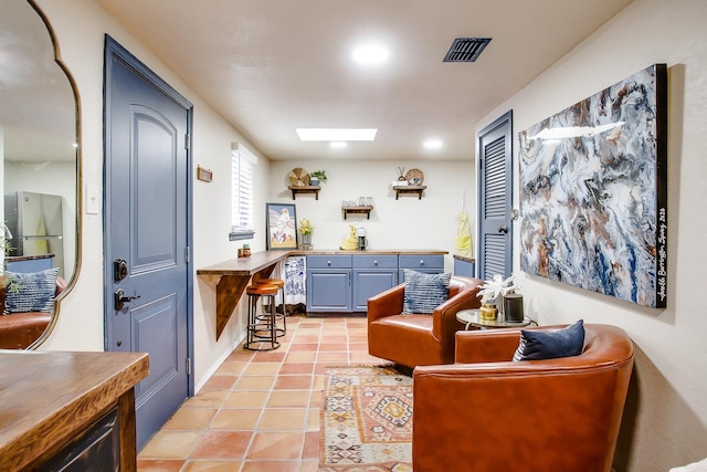 living area featuring light tile patterned floors and a skylight