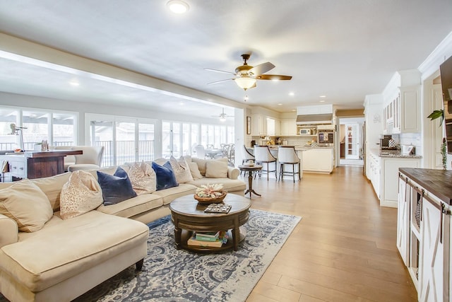 living room with ceiling fan, plenty of natural light, and light hardwood / wood-style floors