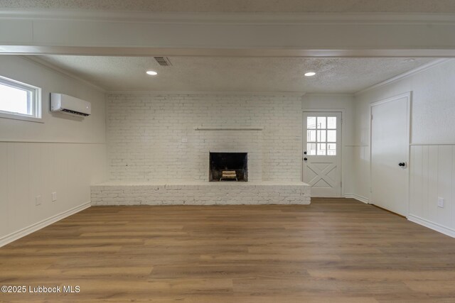 4013 48th St, Lubbock, TX 79413 - unfurnished living room with a wall mounted air conditioner, ornamental molding, wood finished floors, a textured ceiling, and a brick fireplace