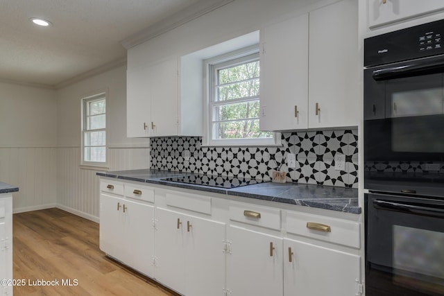 4013 48th St, Lubbock, TX 79413 - kitchen with black appliances, healthy amount of natural light, light wood finished floors, a wainscoted wall, and white cabinetry