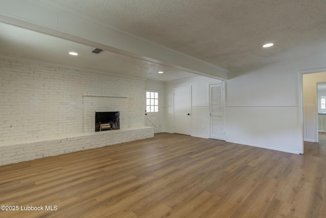 4013 48th St, Lubbock, TX 79413 - unfurnished living room with a textured ceiling, wood finished floors, a fireplace, recessed lighting, and beam ceiling