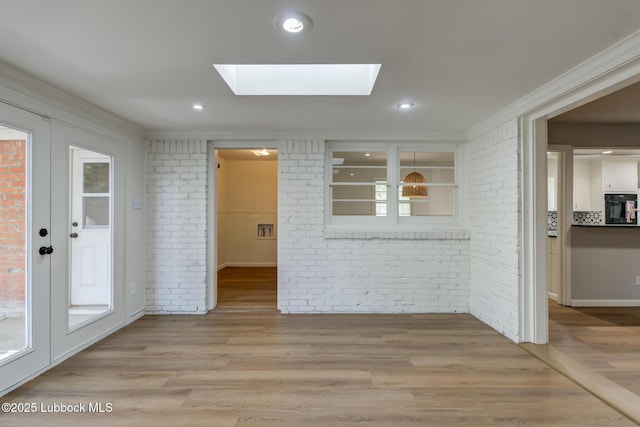 4013 48th St, Lubbock, TX 79413 - unfurnished dining area with brick wall, a skylight, wood finished floors, and ornamental molding