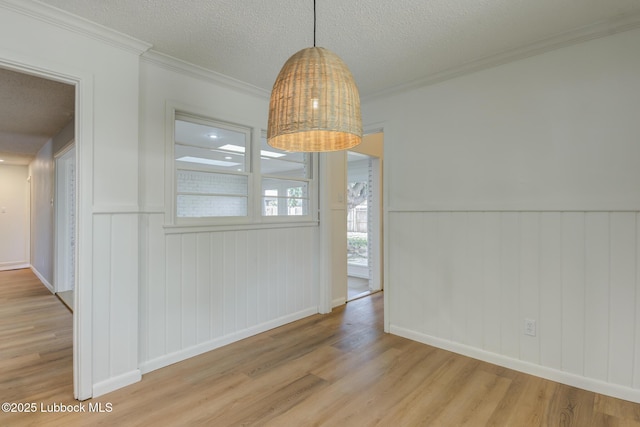 4013 48th St, Lubbock, TX 79413 - unfurnished dining area with light wood finished floors, a textured ceiling, a wainscoted wall, and ornamental molding