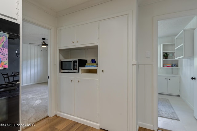 4013 48th St, Lubbock, TX 79413 - kitchen with stainless steel microwave, black oven, ceiling fan, white cabinets, and ornamental molding