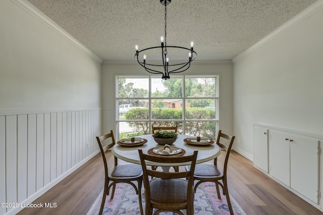 4013 48th St, Lubbock, TX 79413 - dining room with light wood-style floors, a chandelier, a textured ceiling, and ornamental molding
