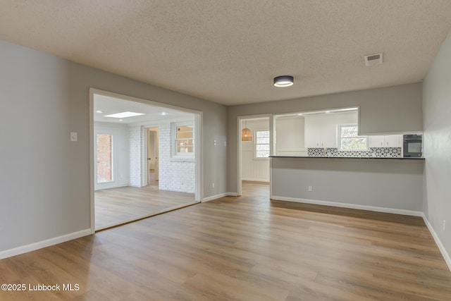 4013 48th St, Lubbock, TX 79413 - unfurnished living room featuring light wood-type flooring and a textured ceiling