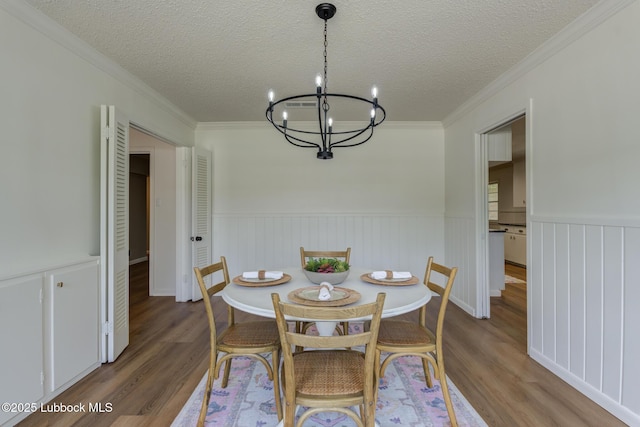 4013 48th St, Lubbock, TX 79413 - dining room with a chandelier, wood finished floors, wainscoting, ornamental molding, and a textured ceiling