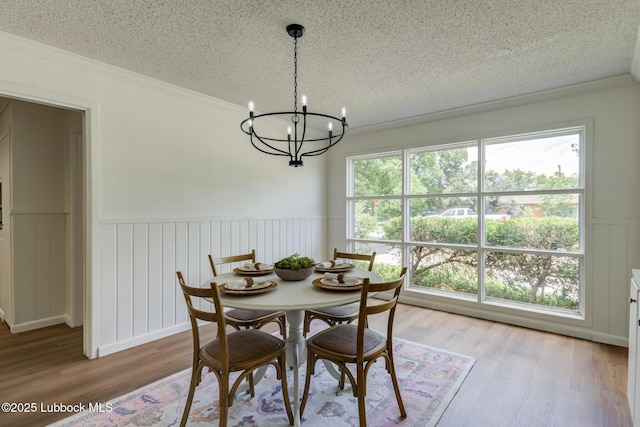 4013 48th St, Lubbock, TX 79413 - dining space featuring a textured ceiling, a chandelier, wainscoting, wood finished floors, and crown molding