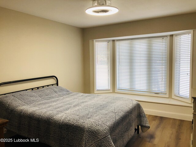 5712 73rd St, Lubbock, TX 79424 - bedroom with wood finished floors, multiple windows, and baseboards