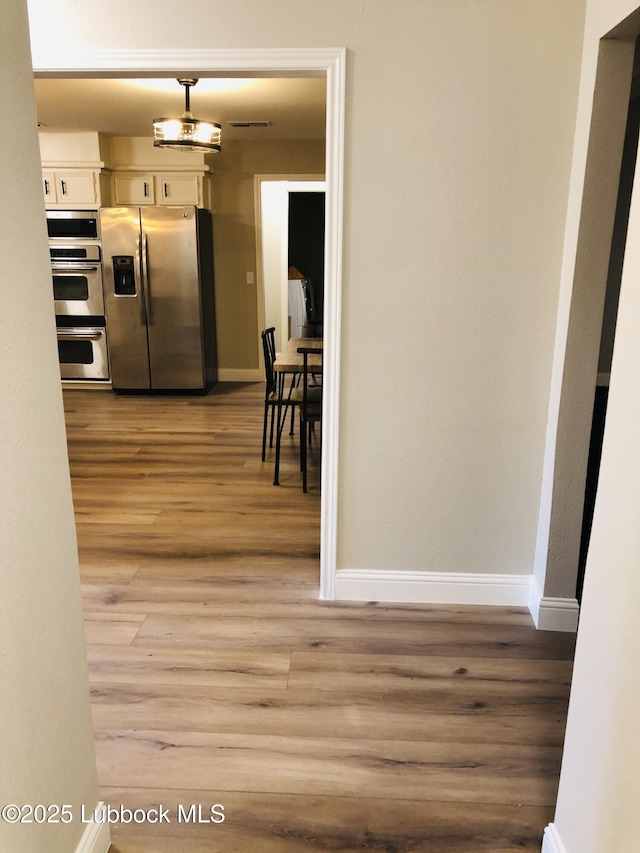 5712 73rd St, Lubbock, TX 79424 - kitchen featuring appliances with stainless steel finishes, light wood-type flooring, baseboards, and white cabinets