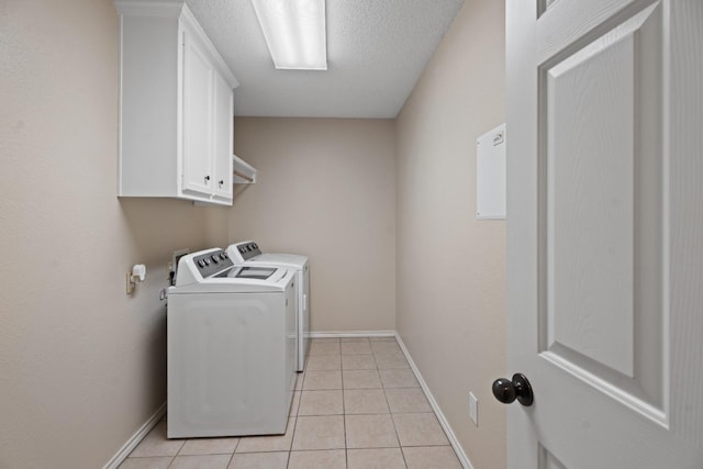 clothes washing area with cabinets, washer and dryer, and light tile patterned floors