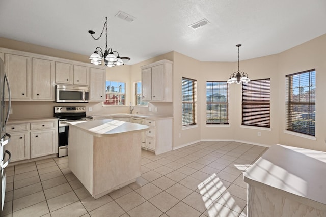 kitchen with hanging light fixtures, light tile patterned floors, a kitchen island, a notable chandelier, and stainless steel appliances