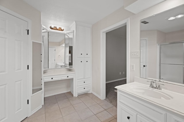 bathroom with vanity, a shower with door, tile patterned flooring, and a textured ceiling