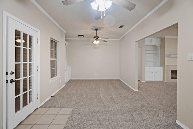 empty room with built in features, a fireplace, light colored carpet, crown molding, and a textured ceiling