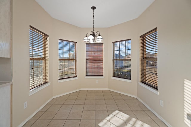 empty room featuring light tile patterned flooring, a wealth of natural light, and a notable chandelier