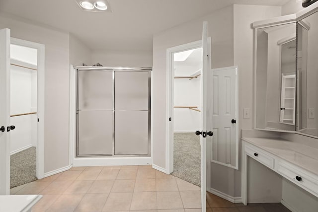 bathroom featuring vanity, a shower with shower door, and tile patterned flooring