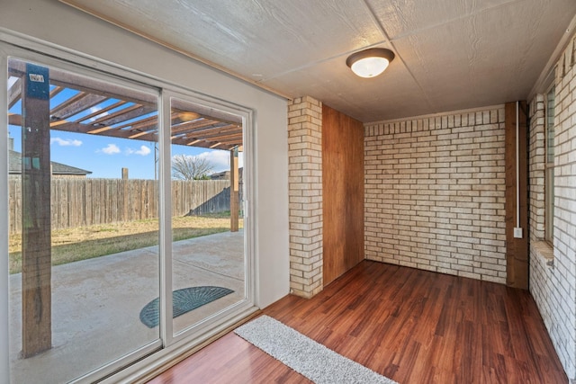 spare room with dark hardwood / wood-style flooring and brick wall