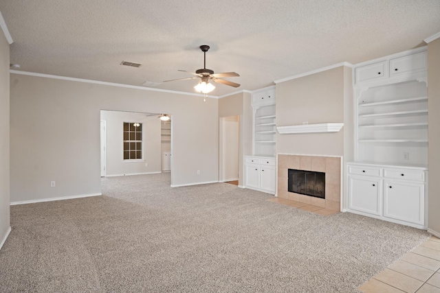 unfurnished living room featuring a textured ceiling, light carpet, visible vents, ornamental molding, and a tiled fireplace