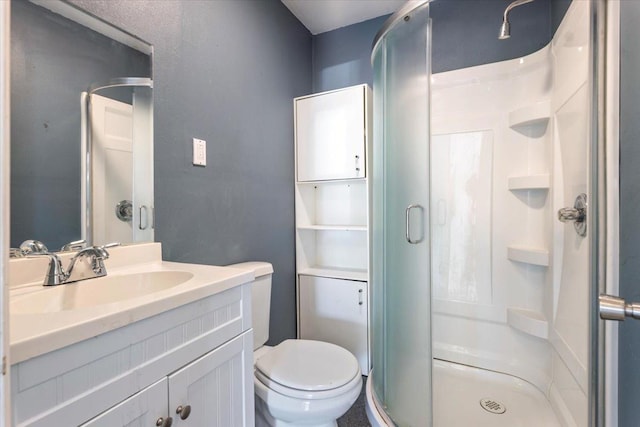 bathroom with vanity, a shower with shower door, and toilet