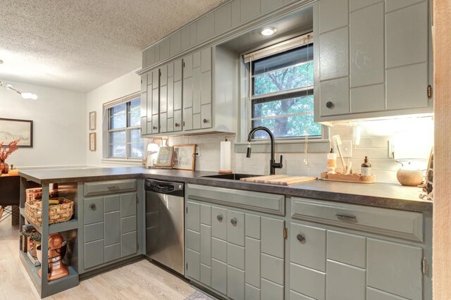 kitchen with sink, gray cabinetry, dishwasher, light hardwood / wood-style floors, and decorative backsplash