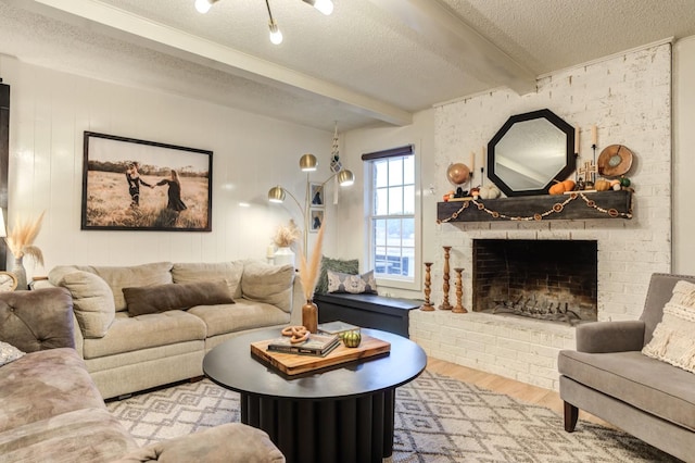 living room with a fireplace, beam ceiling, light hardwood / wood-style flooring, and a textured ceiling