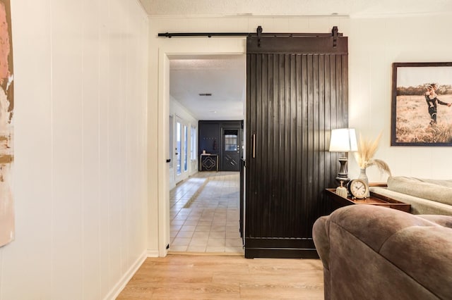 hallway with light hardwood / wood-style floors and a textured ceiling