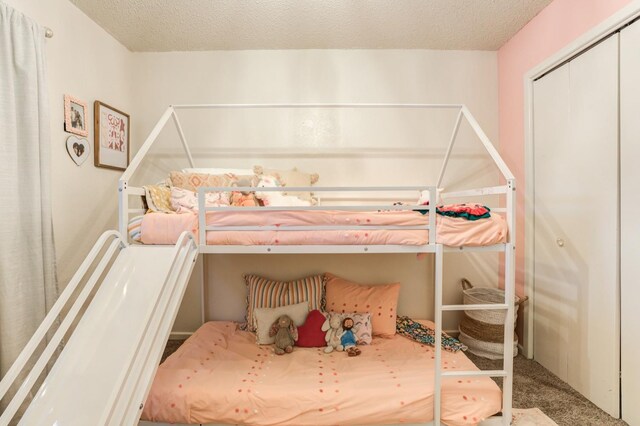 bedroom featuring a closet, a textured ceiling, and carpet flooring