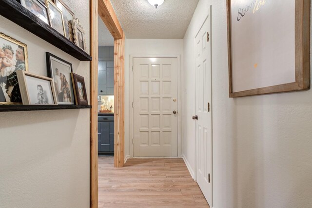 hallway with a textured ceiling and light wood-type flooring