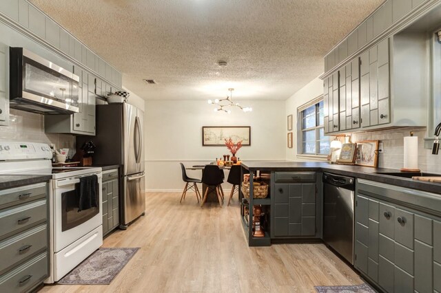 kitchen featuring gray cabinetry, tasteful backsplash, a textured ceiling, and appliances with stainless steel finishes